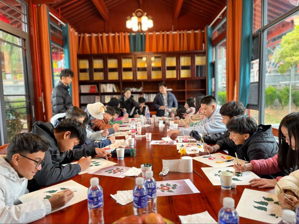 Students participating in drawing activity and learning from a local community in Yunnan during an educational trip.